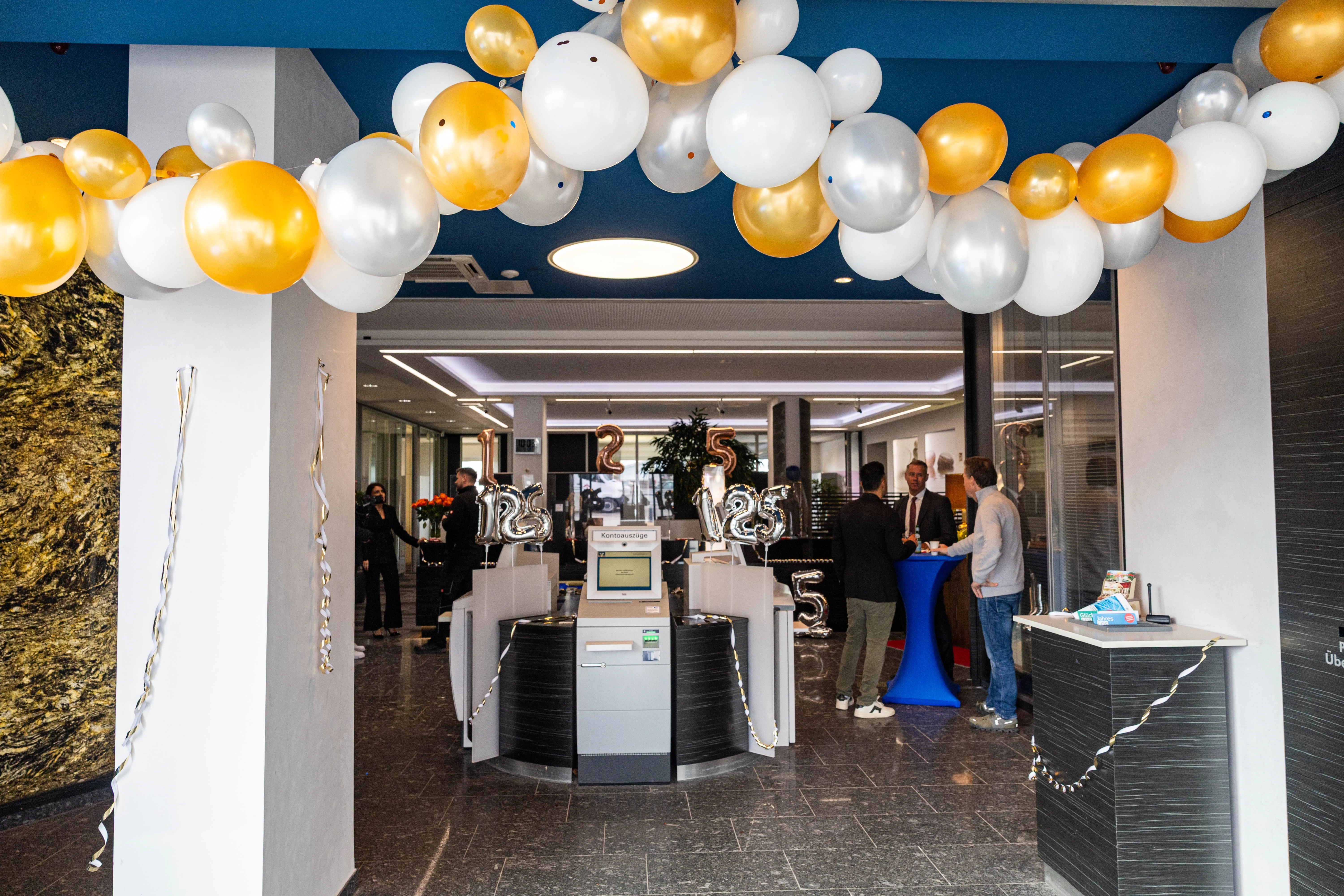 Festlich geschmückter Eingangsbereich der Volksbank Kierspe mit goldenen und weißen Luftballons zum 125-jährigen Jubiläum.