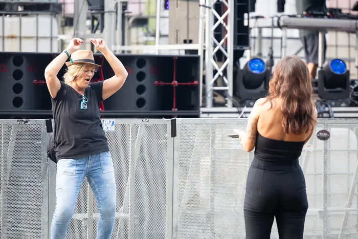 Eine Frau mit Strohhut tanzt mit erhobenen Armen vor einer Bühne bei der Bautz 2026, während eine andere Frau im schwarzen Jumpsuit im Vordergrund steht.