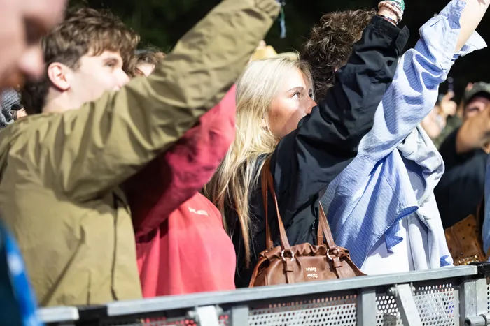Menschen mit erhobenen Armen stehen hinter einer Metallabsperrung an der Turntable Stage.