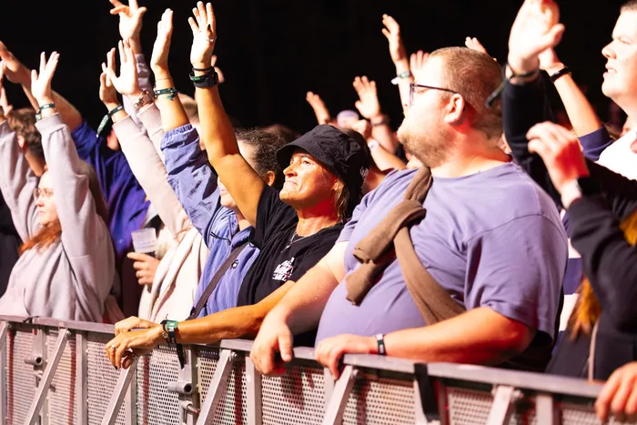 Menschen mit erhobenen Händen stehen vor einer Metallabsperrung bei der Turntable Stage des Bautz 2026.