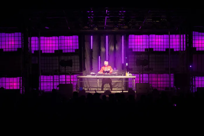 Jan-Christian Zeller performt an einem DJ-Pult auf einer Bühne mit lila Gitterbeleuchtung vor einem Publikum.
