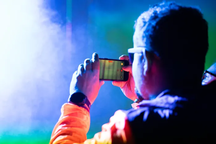 Eine Person filmt mit einem Smartphone die Turntable Stage bei Bautz 2026 unter farbigem Bühnenlicht.