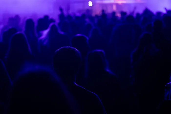 Silhouetten einer Menschenmenge in violettem Licht bei einem Musikereignis.