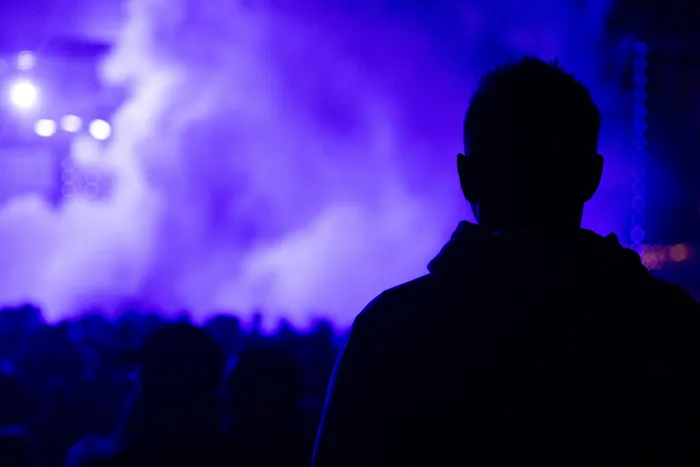 Silhouette einer Person, die auf eine Bühne mit lila Licht und Nebel blickt.