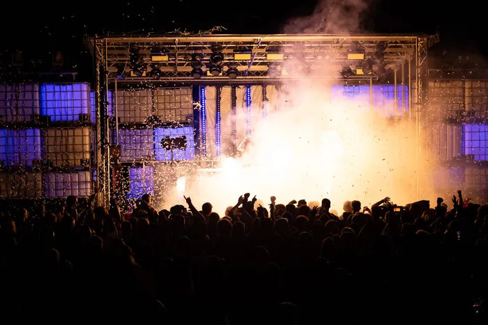 Menschenmenge vor der hell erleuchteten Turntable Stage mit Pyrotechnik und Konfetti in der Luft.