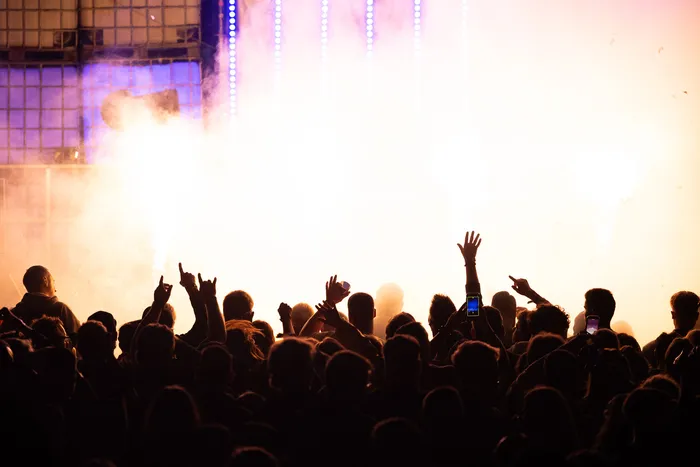 Silhouetten einer Menschenmenge mit erhobenen Händen vor einer hell erleuchteten Bühne mit Lichteffekten und Nebel auf der Lari Luke Turntable Stage.