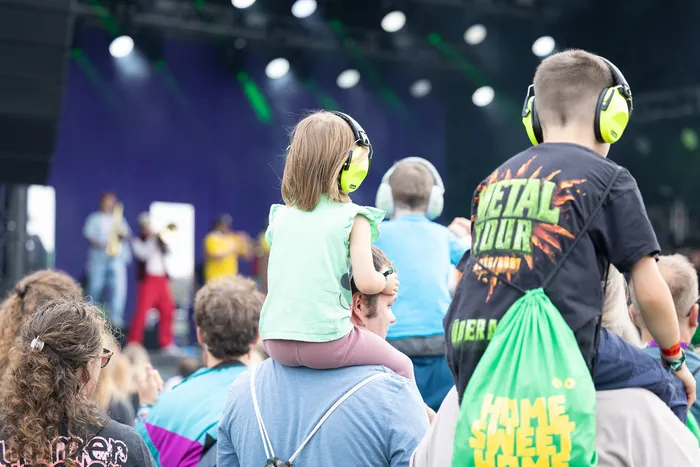 Kinder mit gelben Gehörschützern sitzen auf den Schultern von Begleitpersonen vor der beleuchteten Main Stage beim Bautz 2026 Festival.