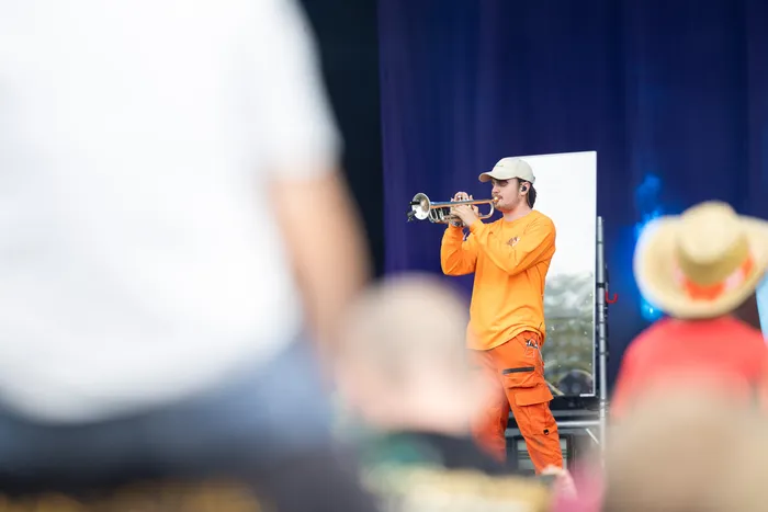 Ein Musiker in orangefarbener Kleidung und weißer Kappe spielt eine Trompete auf der Main Stage beim Bautz 2026.