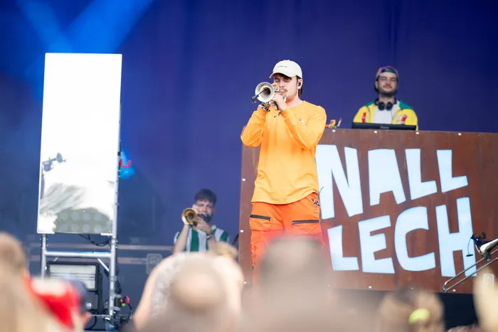 Ein Musiker in orangefarbener Kleidung spielt eine Trompete auf der Main Stage beim Bautz 2026 vor einem DJ-Pult mit der Aufschrift „KNALL LECH“.