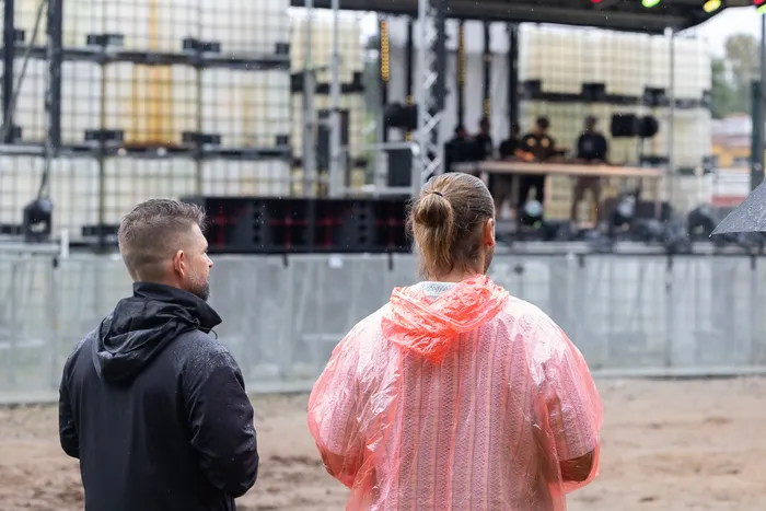 Zwei Männer blicken von hinten auf die Turntable Stage beim Bautz 2026. Einer trägt eine schwarze Jacke, der andere einen pinken Regenmantel.
