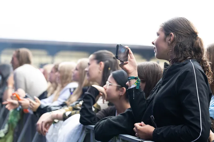 Eine junge Frau hält ihr Smartphone hoch, um die Bühne beim Bautz 2026 zu fotografieren, während sie in einer Menschenmenge steht.