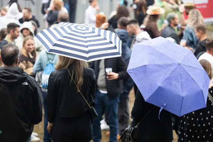 Menschenmenge mit Regenschirmen bei der Bautz 2026 Turntable Stage, im Vordergrund ein blau-weiß gestreifter Schirm.