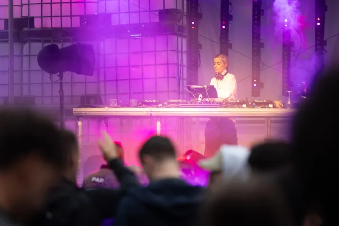 Lovra steht hinter einem DJ-Pult auf der Turntable Stage unter violettem Licht und Bühnennebel.