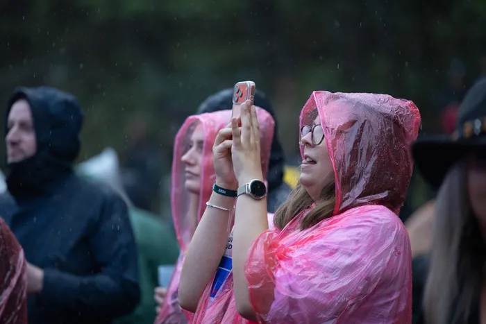 Eine Person in einem pinkfarbenen Regenponcho filmt bei Regen mit ihrem Smartphone auf der Turntable Stage des Bautz 2026 Festivals.