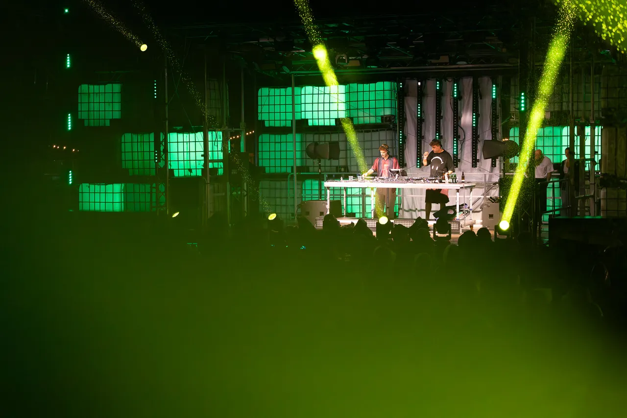 DJ Autobahn und Interplay spielen an einem Mischpult auf der grün beleuchteten Turntable Stage vor einem Publikum.
