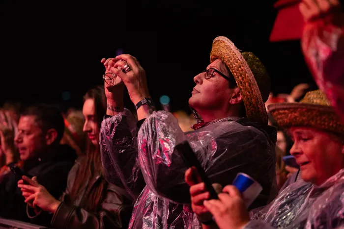 Eine Person mit Strohhut und Regenponcho blickt bei der Bautz 2026 Mainstage während des Alphaville-Auftritts nach oben.