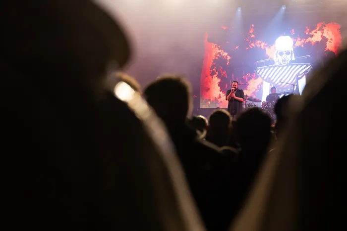 Sänger von Alphaville auf der Mainstage des Bautz 2026 Festivals vor einer großen Leinwand mit einem grafischen Gesicht, im Vordergrund die Silhouetten des Publikums.