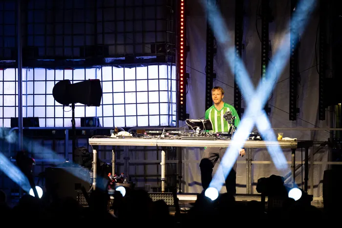Paracek steht hinter einem DJ-Pult auf der Turntable Stage beim Bautz 2026, während helle Lichtstrahlen ein X bilden.