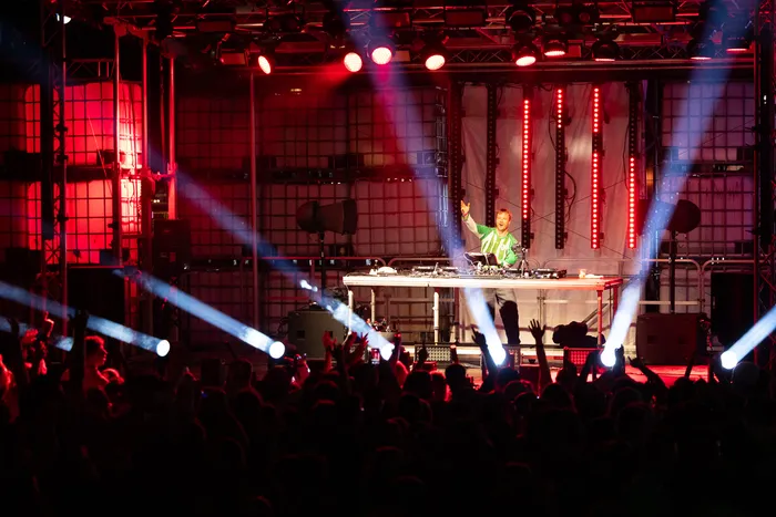 DJ Paracek performt an einem Turntable auf der Bautz 2026 Turntable Stage unter roter Beleuchtung und weißen Lichtstrahlen vor einer Menschenmenge.