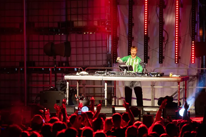 DJ Paracek steht hinter seinem Mischpult auf der Turntable Stage beim Bautz 2026 unter roter Bühnenbeleuchtung.