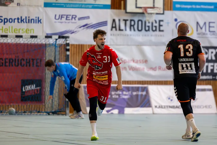 Jubelnder Handballspieler der SGSH Dragons mit der Trikotnummer 31 nach einem Tor, während ein Gegenspieler der Bergischen Panther im Hintergrund abdreht.
