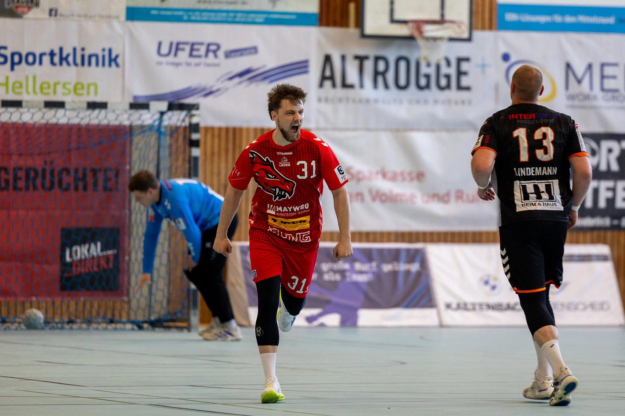 Jubelnder Handballspieler der SGSH Dragons mit der Trikotnummer 31 nach einem Tor, während ein Gegenspieler der Bergischen Panther im Hintergrund abdreht.