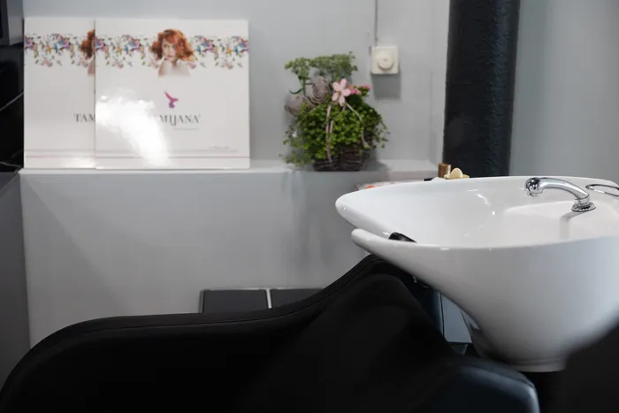 Weißes Waschbecken und schwarzer Friseurstuhl in einem Friseursalon.