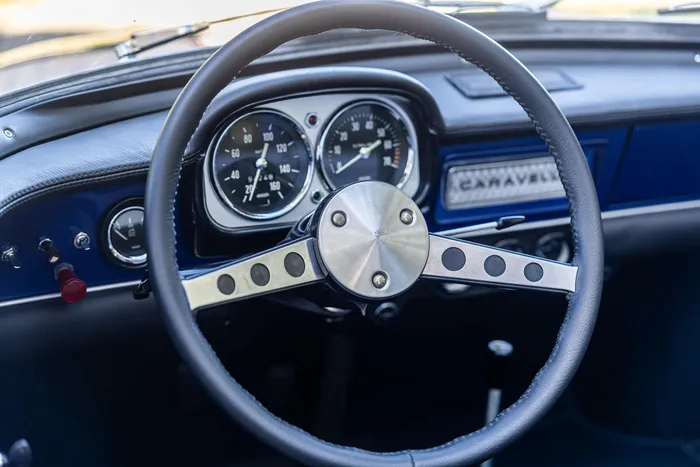 Das Armaturenbrett eines Oldtimers mit schwarzem Lenkrad, analogen Instrumenten und dem Schriftzug „CARAVELLE“.