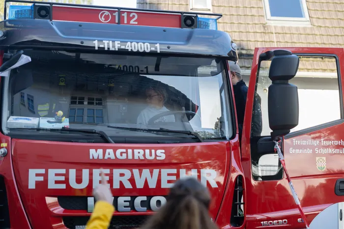 Ein Kind sitzt im Führerhaus eines roten Feuerwehrfahrzeugs.