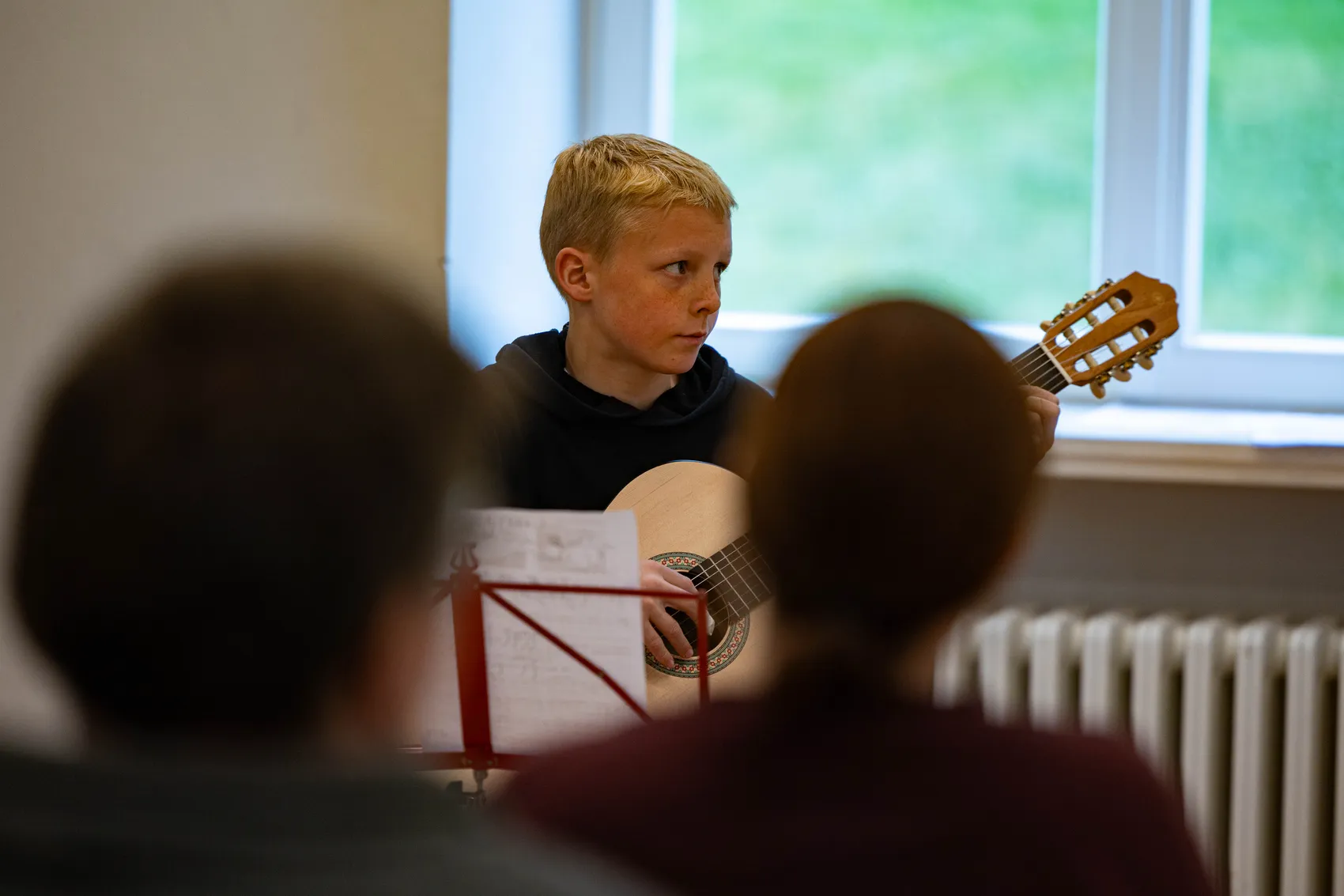 Fynn Morasch spielt Gitarre vor einem Publikum in der Villa am Park während eines Konzerts der Musikschule Volmetal.