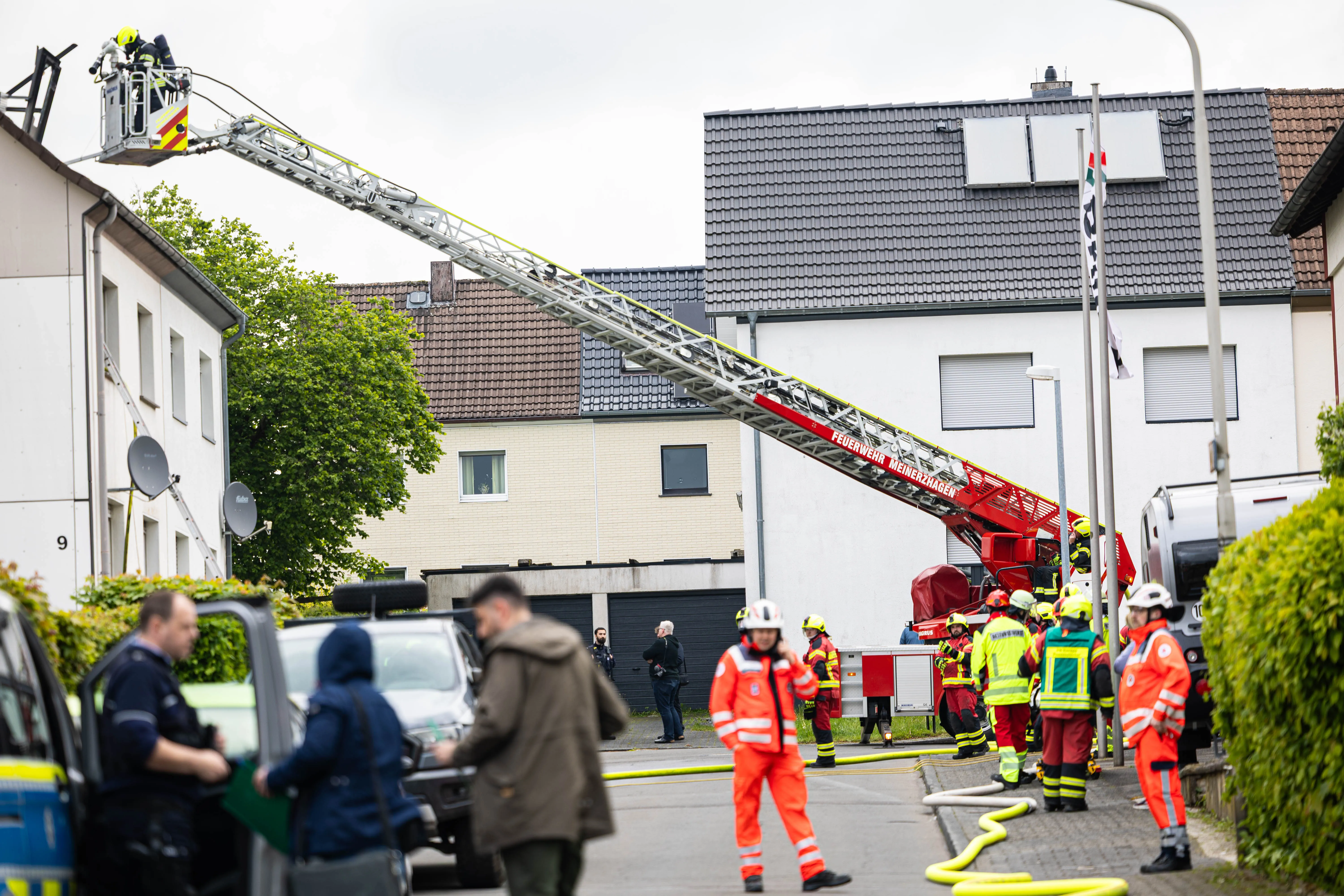 Feuerwehrleute im Einsatz vor einem Wohnhaus in der Gartenstraße Kierspe, ein roter Drehleiterwagen ist ausgefahren.