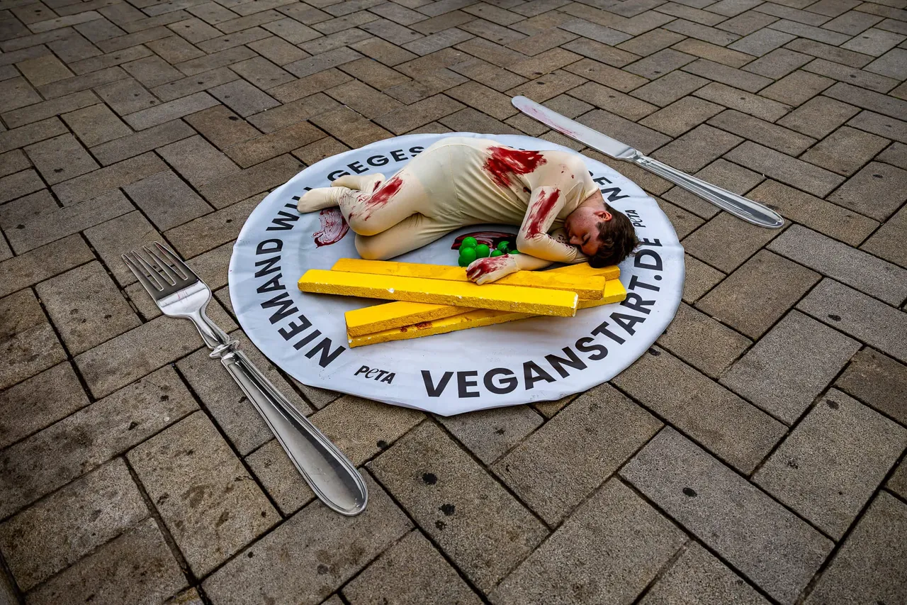 Eine blutverschmierte Person liegt auf einem riesigen Teller mit der Aufschrift „NIEMAND WILL GEGEN VEGANSTART.DE“ neben einer überdimensionalen Gabel und einem Messer.