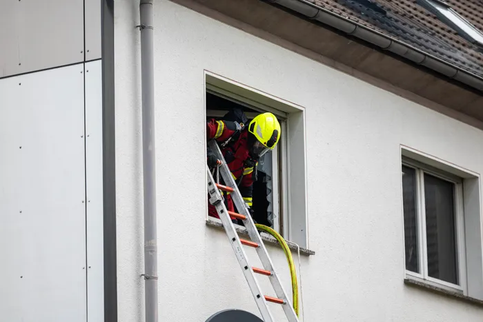 Feuerwehrmann in voller Montur klettert mit einer Leiter in ein Fenster eines hellen Gebäudes während eines Einsatzes in der Gartenstraße.