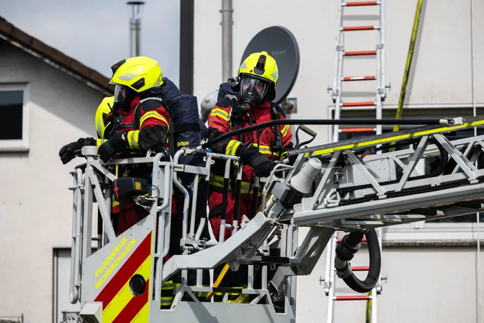 Drei Feuerwehrleute in voller Montur bedienen eine Hebebühne während eines Einsatzes in der Gartenstraße.