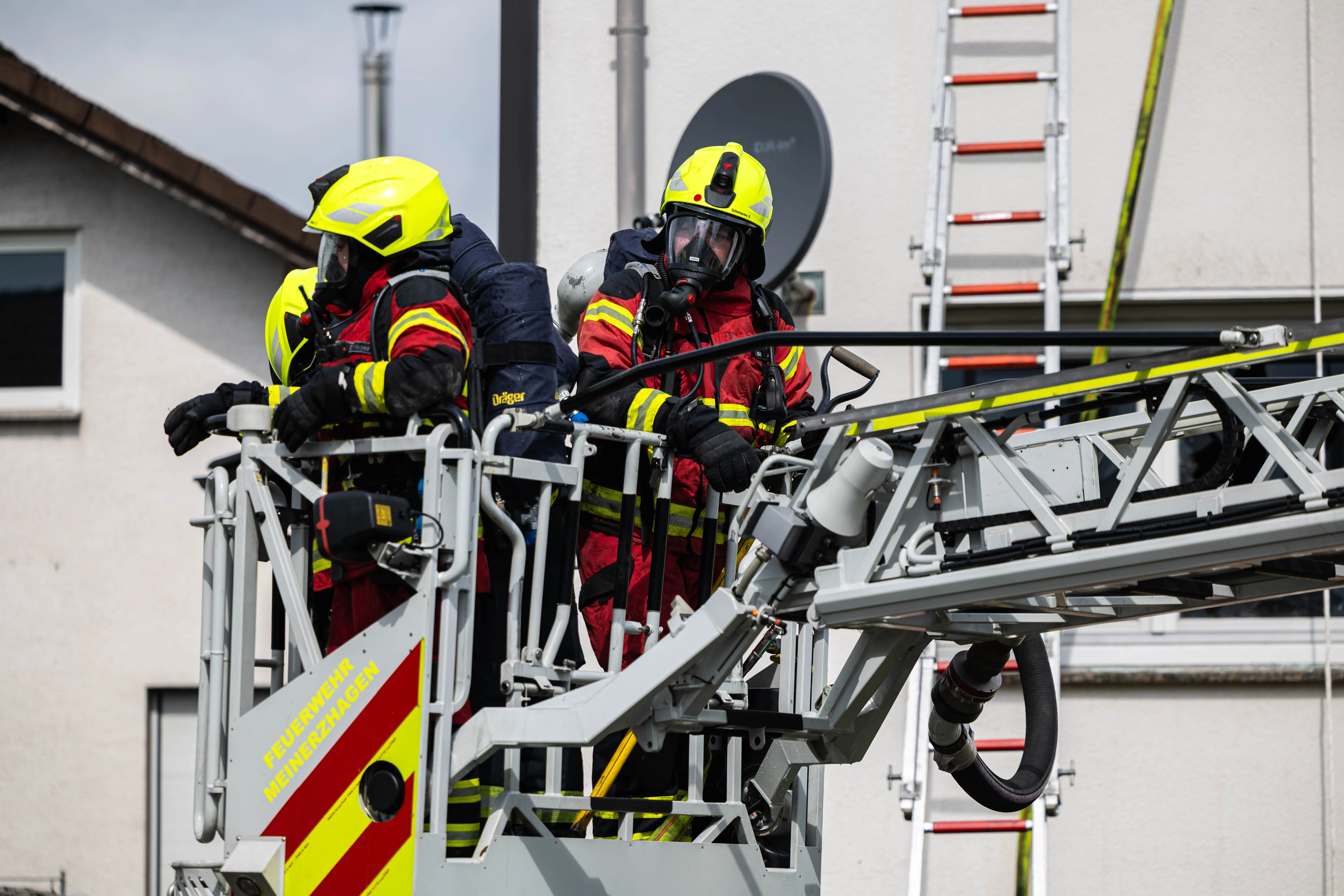 Drei Feuerwehrleute in voller Montur bedienen eine Hebebühne während eines Einsatzes in der Gartenstraße.