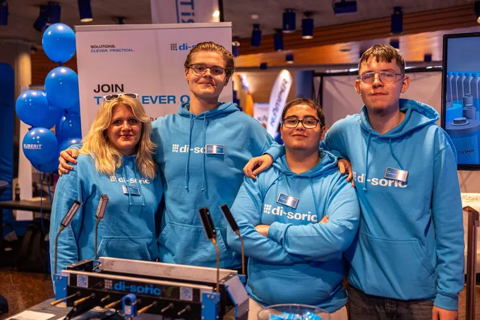 Vier Personen in blauen Hoodies mit dem „di-soric“-Logo posieren auf der ZAK-Ausbildungsmesse.