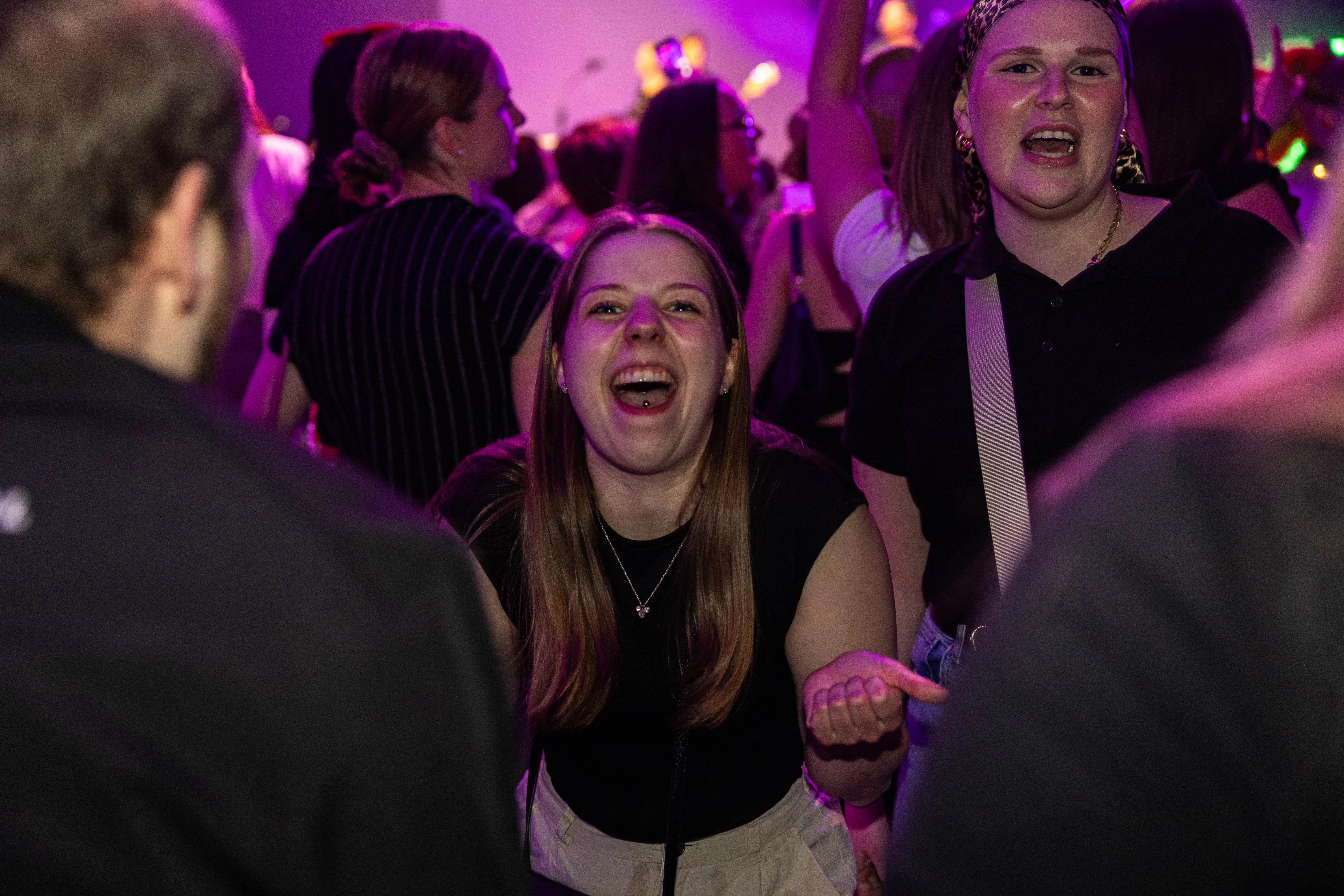 Zwei junge Frauen singen enthusiastisch mit, umgeben von einer jubelnden Menge auf dem Kölschmusikfestival Valberta Colonia.