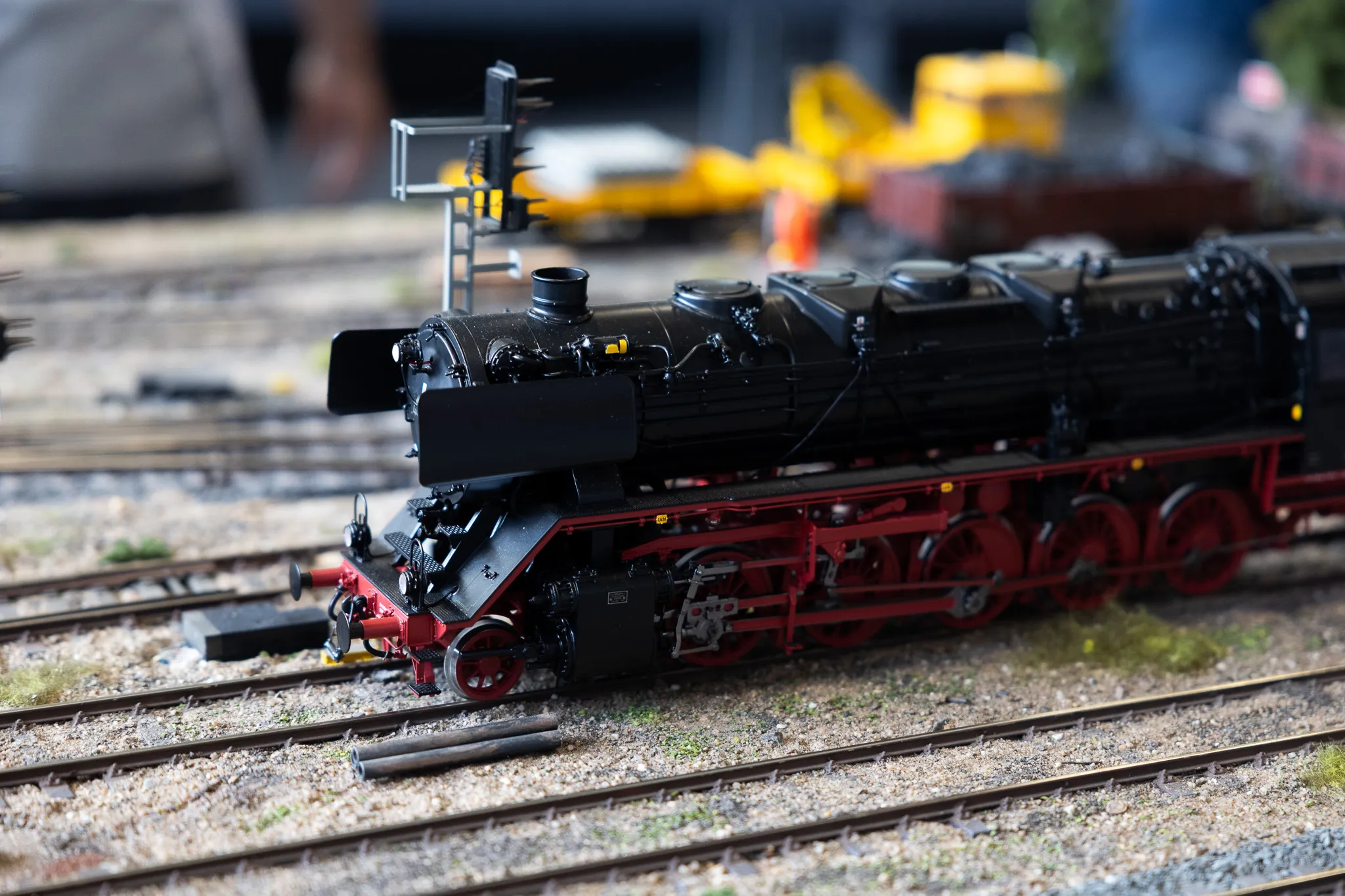 Detailliertes Modell einer schwarzen Dampflok mit roten Rädern auf Gleisen einer Modellbahn.
