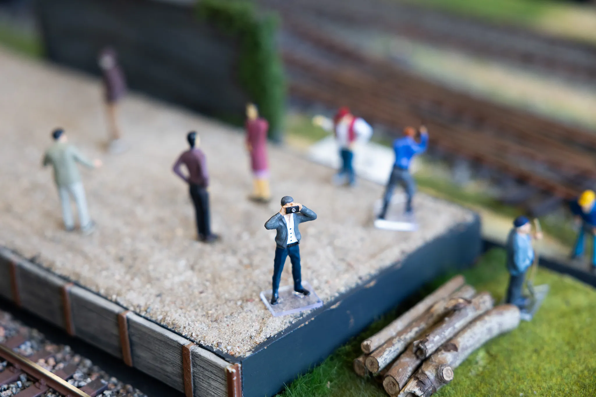 Miniaturfiguren auf einer Modellbahnanlage zeigen einen Fotografen bei der Arbeit und umstehende Personen.