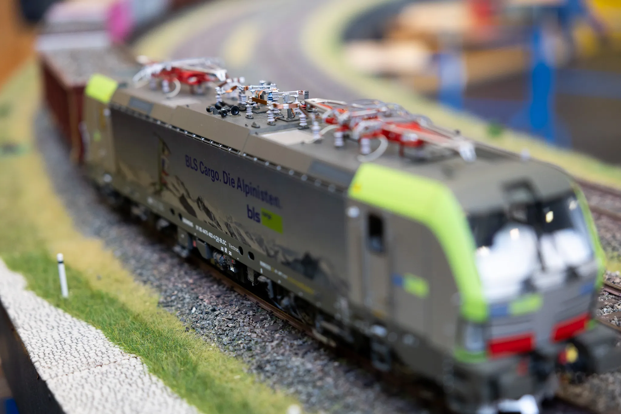 Modell einer grauen Lokomotive mit grünen Akzenten und dem Aufdruck „BLS Cargo. Die Alpinisten“ auf Schienen.