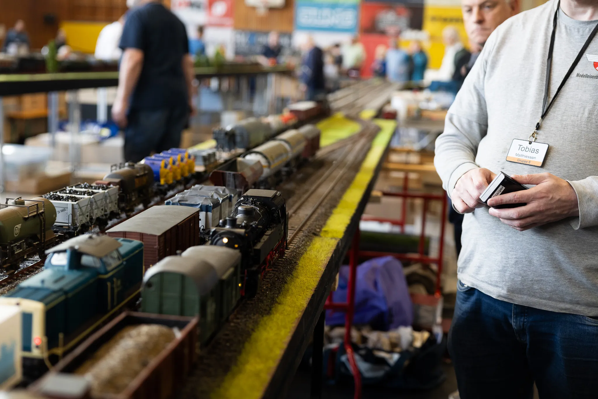 Ein Mann betrachtet eine detaillierte Modelleisenbahnanlage mit verschiedenen Waggons und einer Dampflokomotive auf Gleisen.