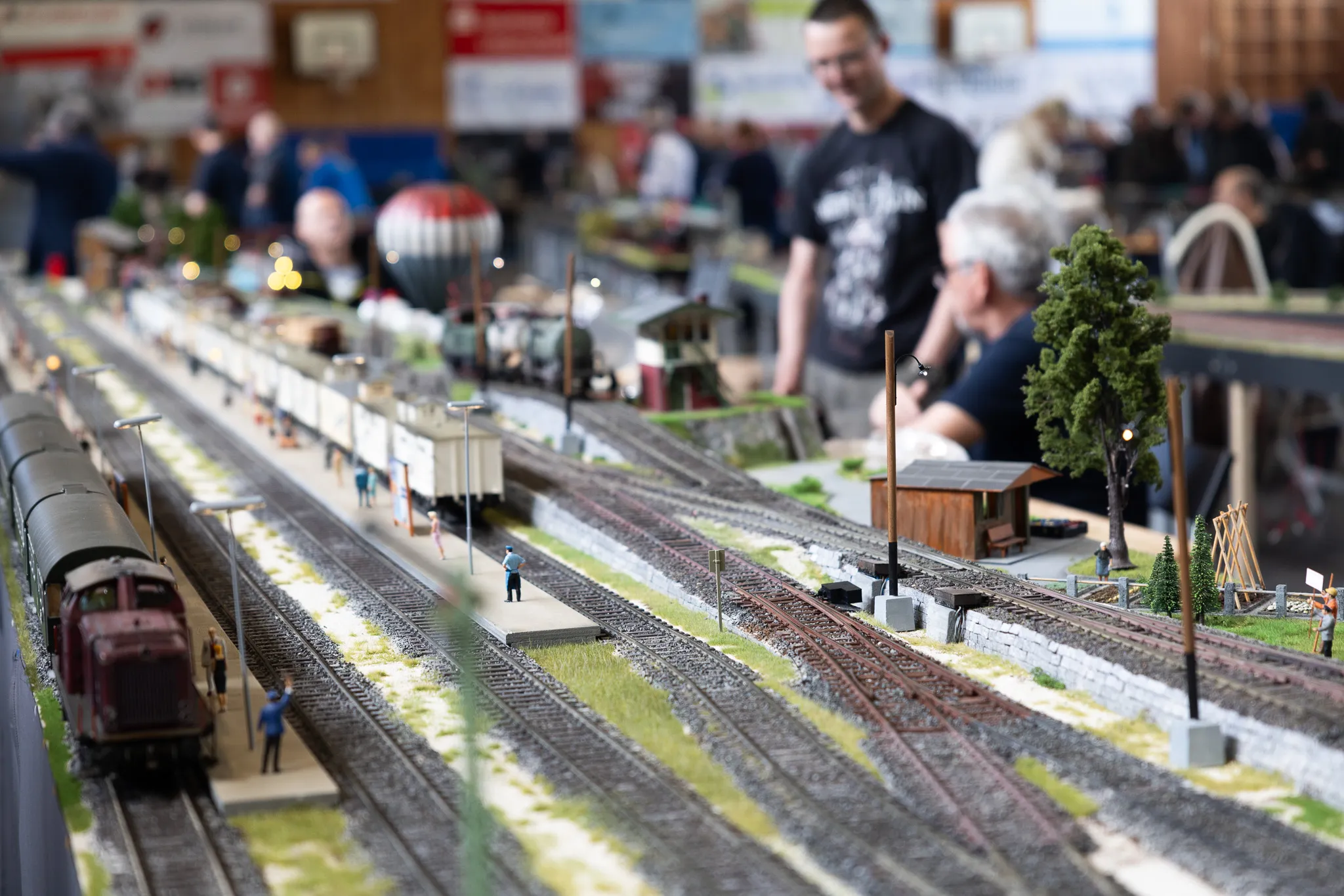 Detailreiche Modellbahnlandschaft mit Zügen, Gleisen und kleinen Figuren zieht Besucher an.