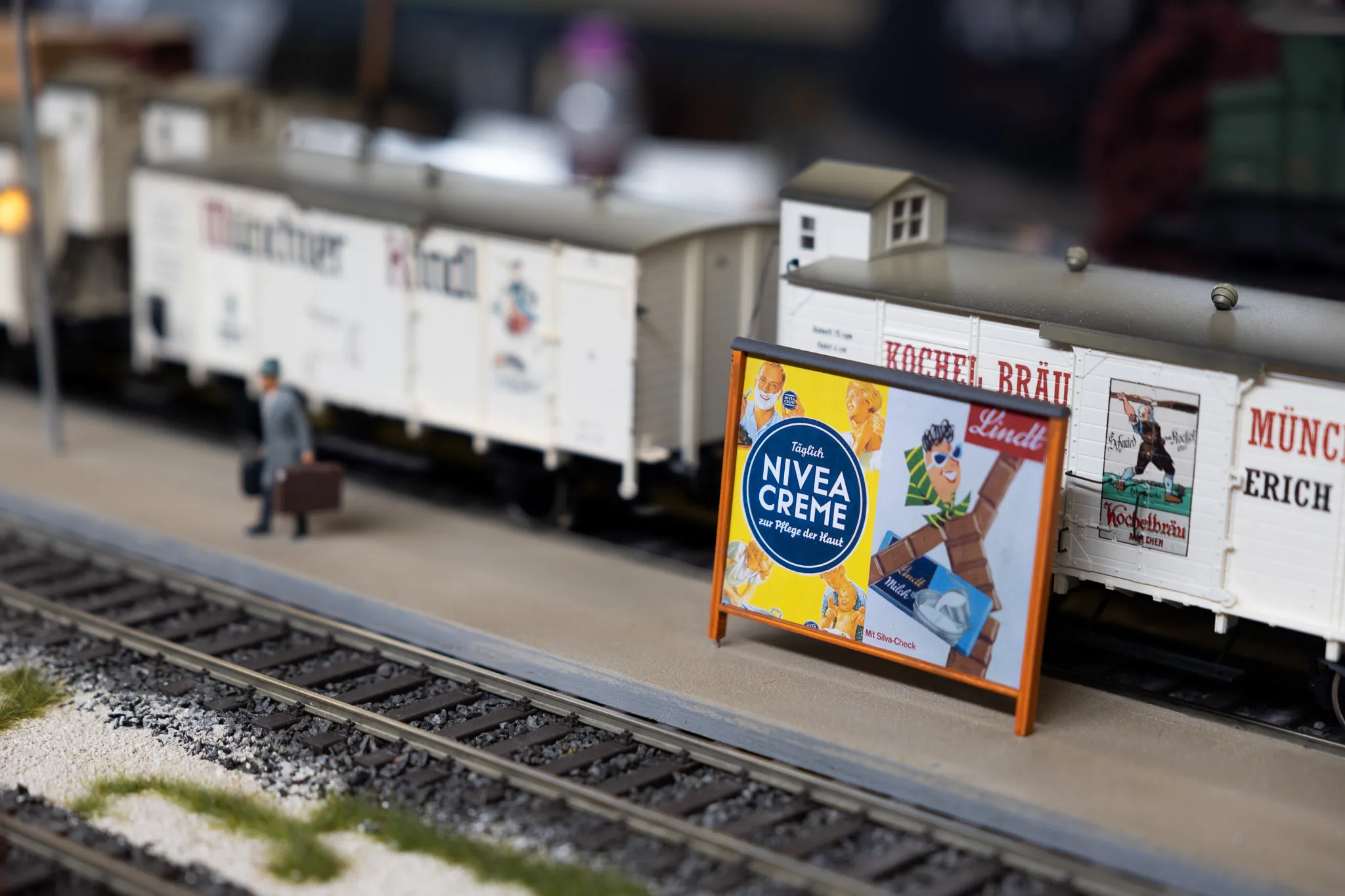 Modellbahn-Güterwagen mit Werbeplakaten für Nivea Creme und Lindt Schokolade auf Gleisen.