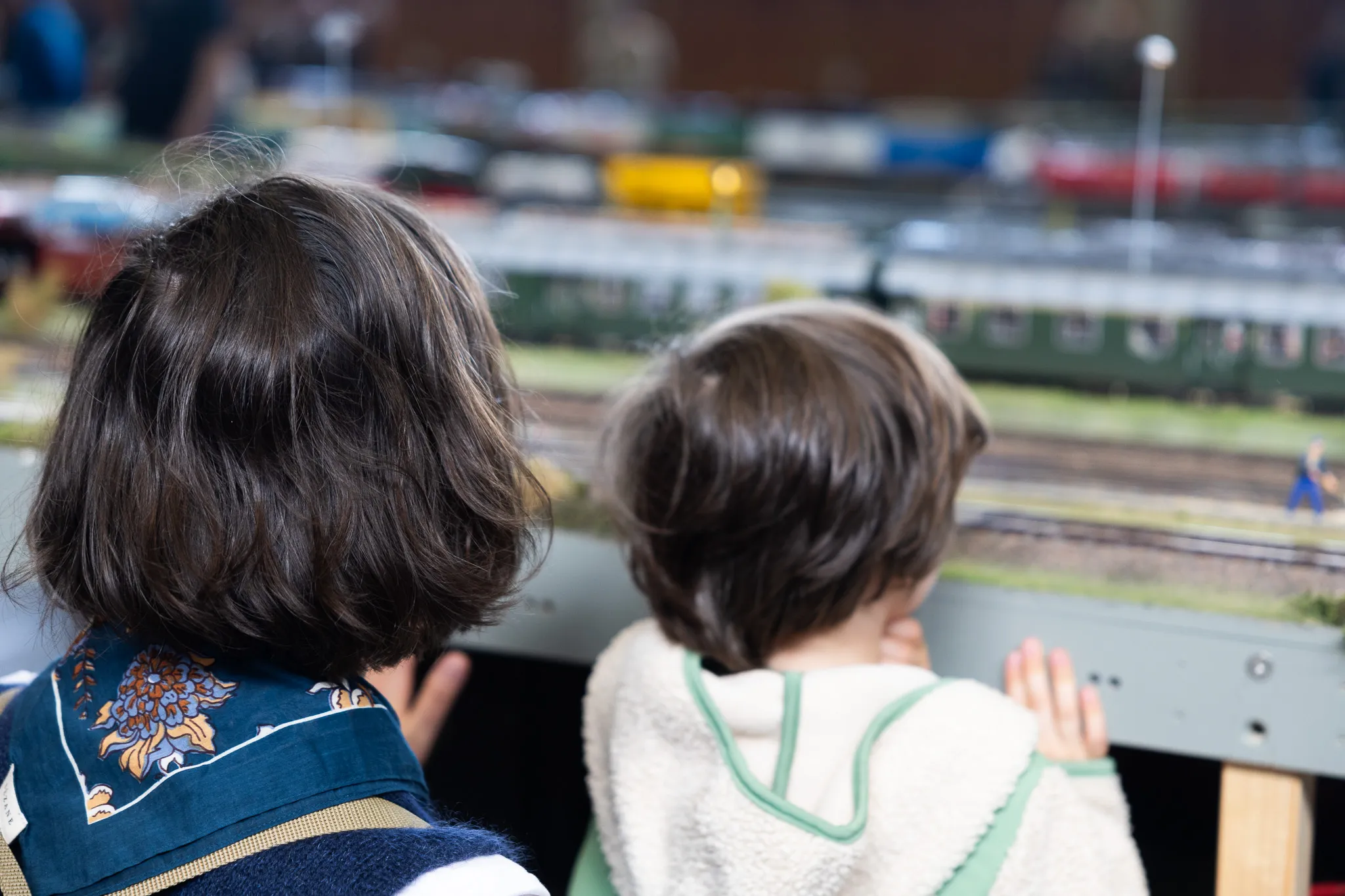 Zwei Personen betrachten eine detailreiche Modellbahnlandschaft mit Zügen und Gebäuden.