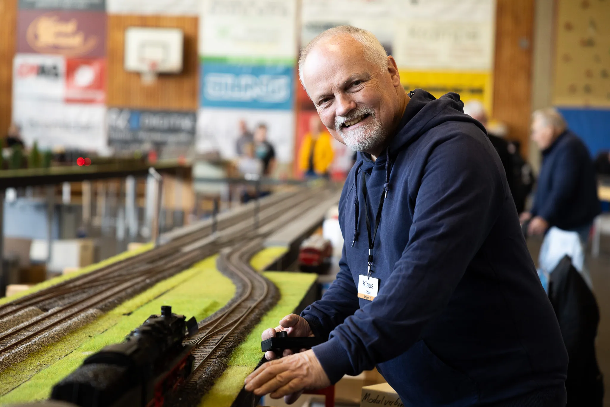 Ein Mann mittleren Alters bedient eine Modelleisenbahn auf einer Ausstellung. Er trägt einen Namensschild mit der Aufschrift „Klaus“.