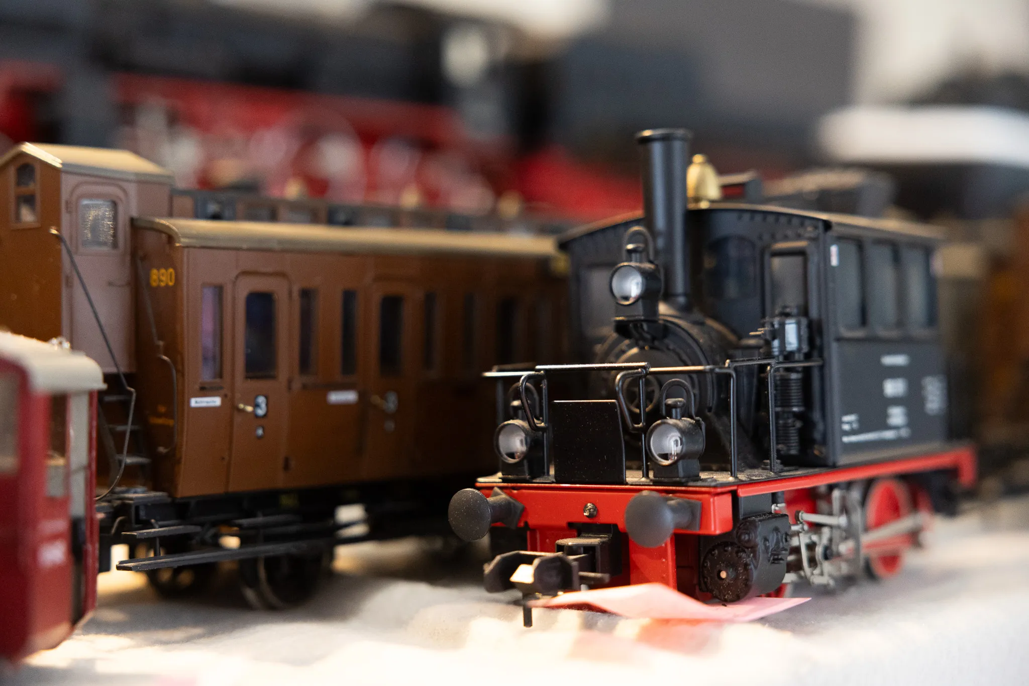 Detailaufnahme einer Dampflok und eines Waggons einer Modellbahn auf einer Ausstellungsfläche.