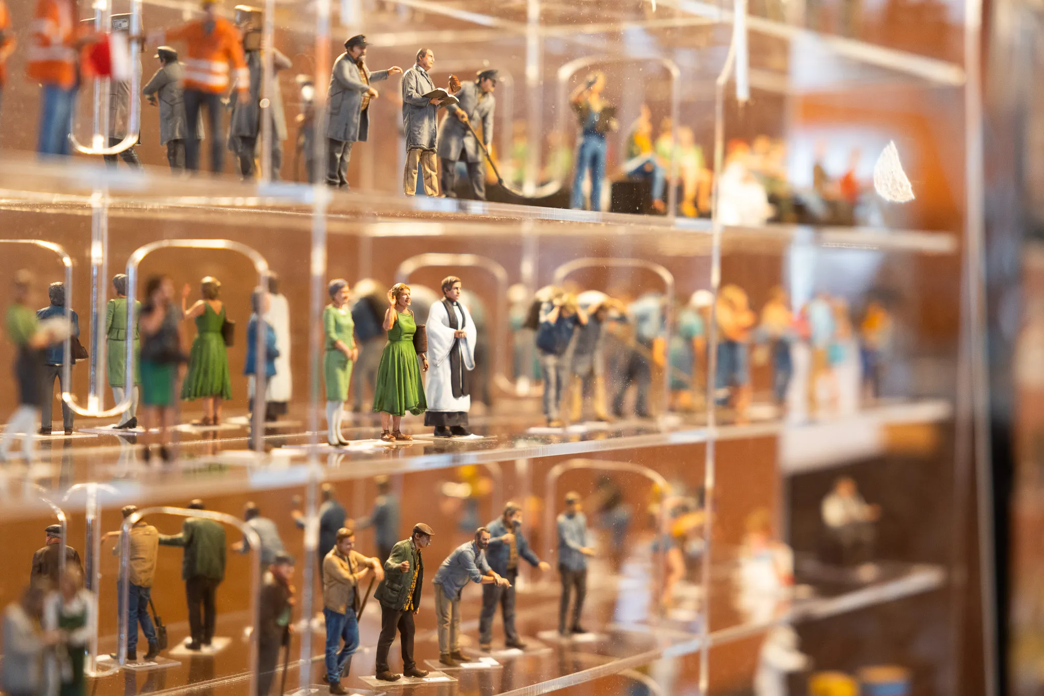 Mehrere Reihen von detailreichen Modellfiguren in einer Vitrine, die eine Miniaturlandschaft darstellen.