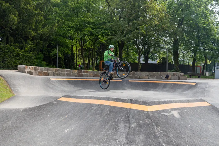 Ein Radfahrer springt mit seinem Fahrrad über eine Rampe im neu eröffneten Pumptrack im Lüdenscheider Stadtgarten.