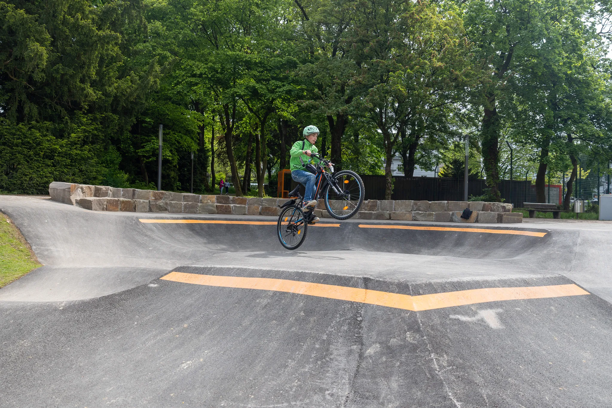 Ein Radfahrer springt mit seinem Fahrrad über eine Rampe im neu eröffneten Pumptrack im Lüdenscheider Stadtgarten.