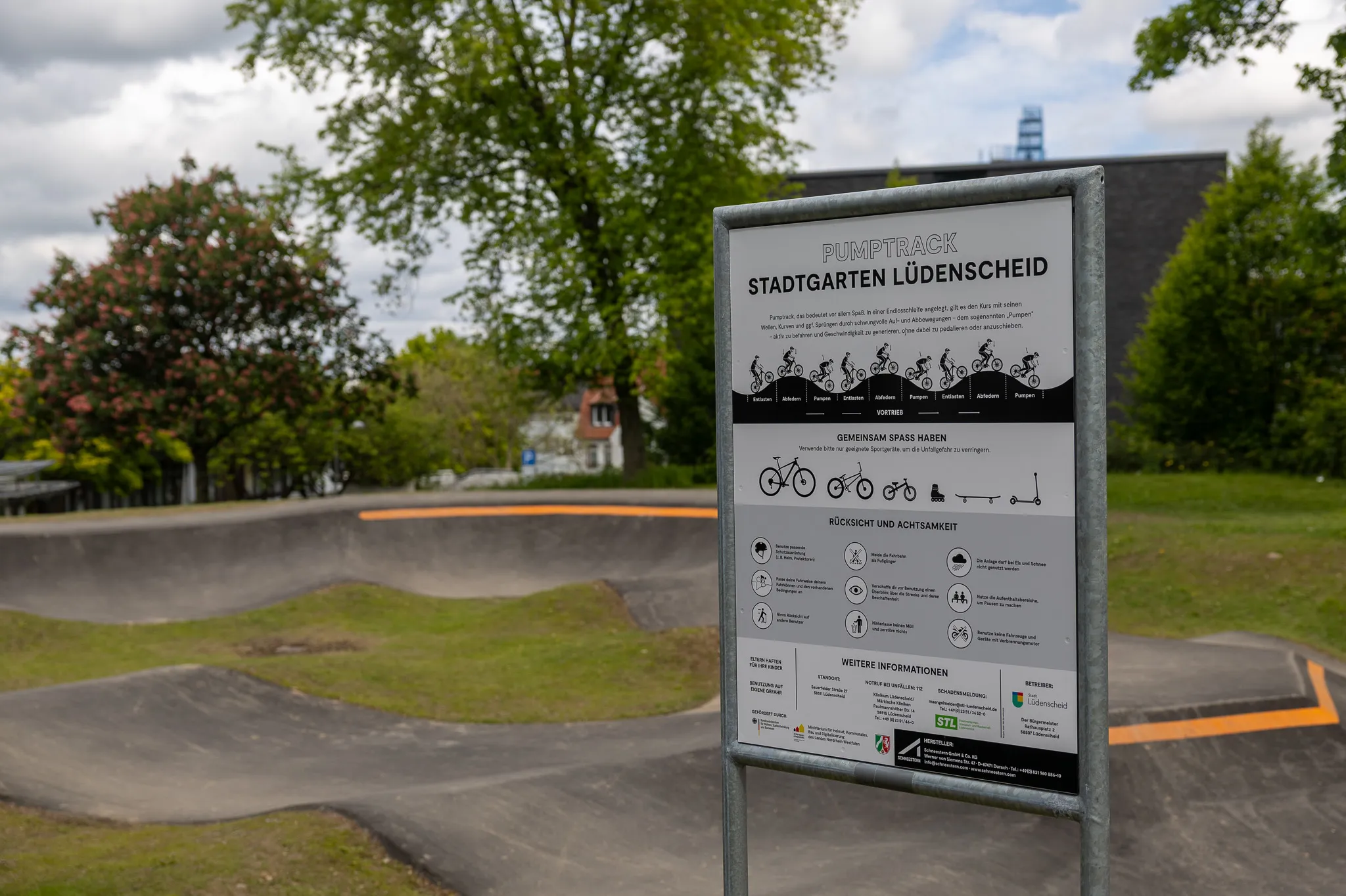 Schild am Eingang zum Pumptrack im Stadtgarten Lüdenscheid mit Informationen zu Nutzung, Regeln und weiteren Angeboten des Parks.